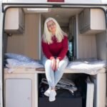 Interior view of motorhome showing drop-down bed mechanism above seating area in lowered position