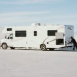 Motorhome vs Campervan: What's the Difference? Side-by-side comparison of a motorhome and campervan parked at a scenic campsite illustrating the differences in size and design